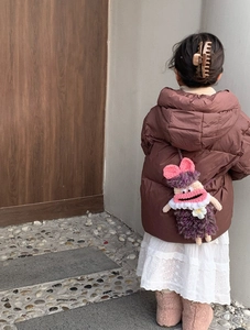 Detail of child wearing a purple hand-knitted monster crossbody bag with a pink bow