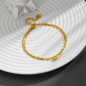 Double-layered gold titanium steel bracelet with a round zircon pendant on white ceramic