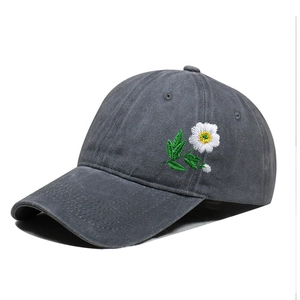 Close-up of intricate white daisy embroidery on vintage washed grey cotton baseball cap