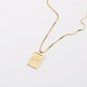 Detailed close-up of a golden square pendant with sun and cloud relief on a box chain