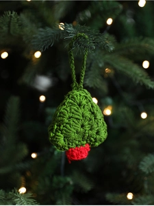 Close-up of handmade crochet Christmas tree ornament with green texture and red base