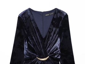 Detailed view of the deep blue velvet dress featuring a V-neck and a gold buckle accent