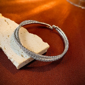 Macro shot of silver double-row zircon pavé cross bangle with a minimalist design
