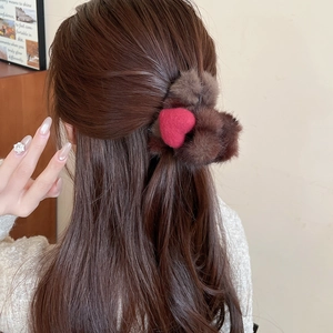 Détail d'une pince à cheveux en peluche avec cœur marron portée en demi-queue
