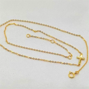 Detail of gold cross pendant necklace featuring spring clasp and adjustable chain