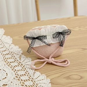 Détail du sac tissé rose avec bordure en dentelle blanche et nœuds noirs décoratifs
