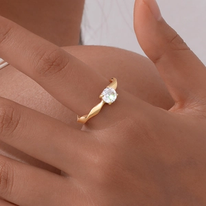 Close-up of golden Mobius ring with a sparkling round zircon on a finger