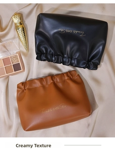 Close-up of pleated PU cosmetic bags in black and tan on champagne satin fabric