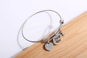 Detail van verstelbare roestvrijstalen armband met gegraveerde hart en True Love bedels