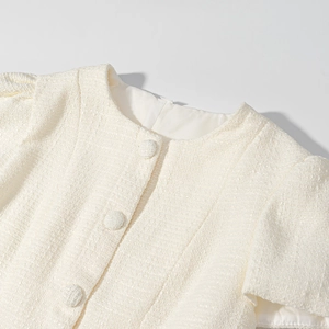 Dettaglio della giacca in tweed bianco crema con trama ricca e bottoni in tessuto