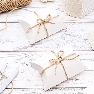 White pillow-shaped paper gift boxes with natural twine for wedding favors and party candy