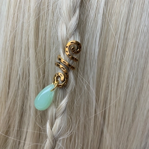 Detail of gold spiral hair jewelry with green teardrop crystal pendant on blonde braid