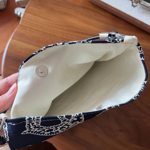 Macro view of navy canvas bag showing white embroidery and silver magnetic buckle