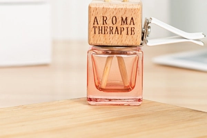 Macro detail of a square glass perfume bottle with a wooden lid and vent clip for car aroma
