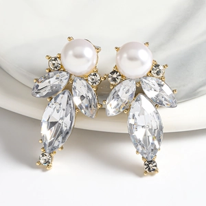 Elegant gold drop earrings with white pearls and sparkling leaf-shaped crystals on ceramic