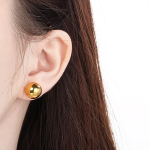 Detailed close-up of a glossy gold spherical earring worn by a professional model