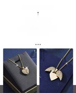 Detail of a gold heart locket necklace opening into wings with sparkling pavé stones