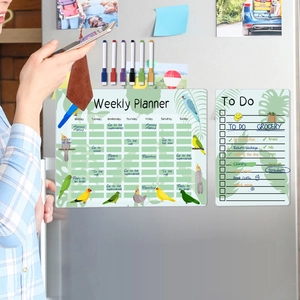 Close-up of magnetic weekly planner and to-do list with parrot design on a steel fridge