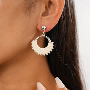 Close-up of a silver geometric round earring with beige woven leather on a female model