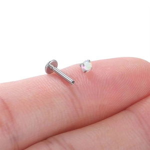 Macro shot of a small stainless steel labret stud with a shiny opal stone inlay