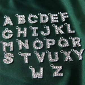 Detailed view of 26 silver alloy alphabet charms with rhinestones on silk