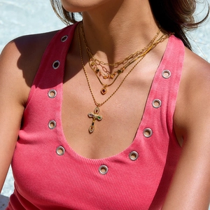 Close-up of layered 18K gold plated stainless steel necklaces with orange heart and cross charms