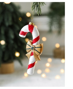 Close-up of a red and white candy cane ornament with a gold bow on a Christmas tree