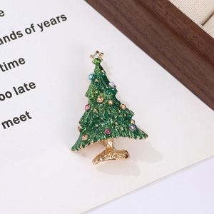 Detailed view of a green enamel Christmas tree brooch with colorful rhinestones on a gold base