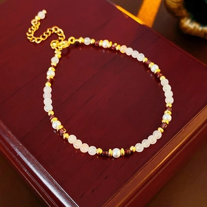 Macro shot of 18K gold plated pearl and garnet bracelet on vintage wood jewelry box