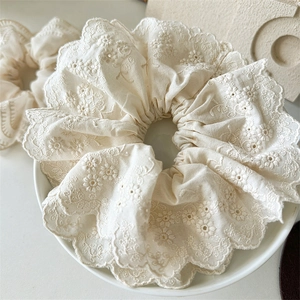 Détail d'un chouchou en dentelle crème avec broderie florale et bords festonnés sur assiette