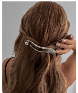 Macro detail of a silver metal hairpin elegant pearl clip on brown wavy hair