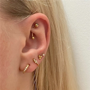 Detail of gold ear stack set with lightning and bead studs featuring white zircon stones