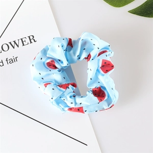 Close-up of light blue watermelon print scrunchie made of soft fabric for summer
