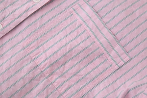 Détail d'une chemise rayée rose en coton avec boutons blancs et une poche plaquée carrée