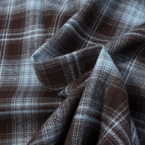 Macro shot of brown flannel fabric with soft brushed texture and blue plaid pattern