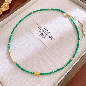 Natural green stone and pearl necklace with gold heart pendant on beige tray