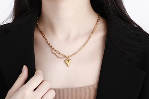 Dettaglio della collana dorata con pendente a cuore e catena a maglie miste