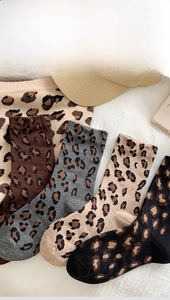 Flat lay of leopard print crew socks in four colors with matching knitted background