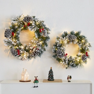 Green Christmas wreath set with pine cones and red berries with warm LED lights