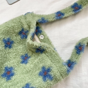 Close-up of green plush tote bag with flower pattern and silver snap button closure
