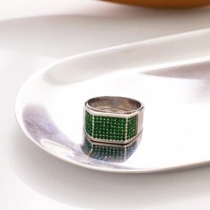 Macro detail of silver ring with pave-set green crystals on a rectangle face