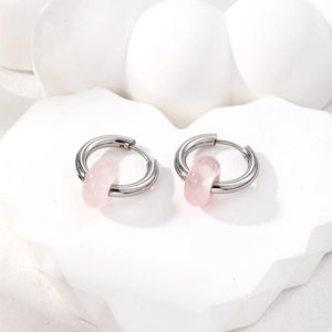 Detail of silver stainless steel hoop earrings featuring translucent pink stone beads