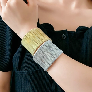 Primo piano di bracciali rigidi a fili avvolti oro e argento sovrapposti sul polso