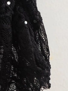 Détail du tissu en dentelle noire avec ornements en strass argentés et maille