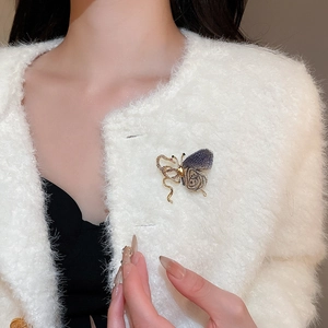 Detail of a butterfly brooch with gold alloy and dark blue mesh on a white coat