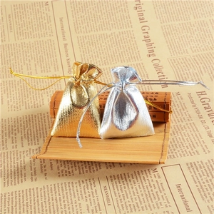 Detailed view of metallic gold and silver drawstring jewelry pouches on bamboo mat