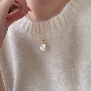 Detailed view of 925 sterling silver angel shell pendant on a gold chain over a soft sweater