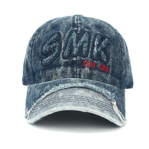 Détail de la visière usée et broderie SMK sur la casquette en jean bleu vintage