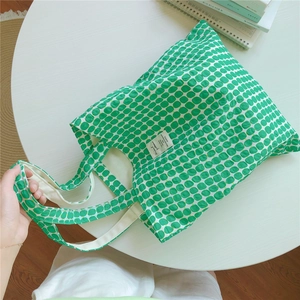 Close-up of green and cream polka dot cotton tote bag with stylish fabric label detail