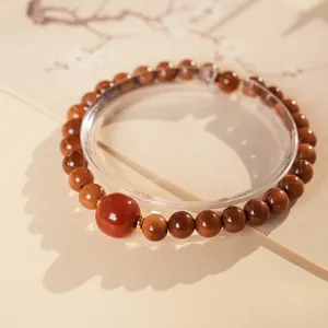 Polished Kuka wood bead bracelet with red agate accent and golden spacers on stand